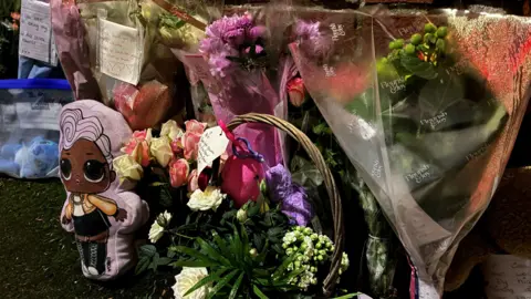 A row of bouquets of flowers are seen lined up on a roadside in Weston-super-Mare. The picture is taken after dark