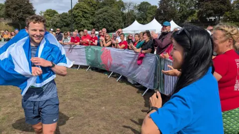 Steven Parrish A runner finishing a race with a flag wrapped around his shoulders