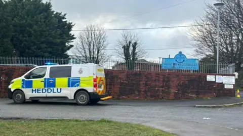 Pembrokeshire Herald A brown school wall with a silver railing above and a police van parked outside. In the background is a blue school sign.
