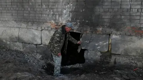 Reuters A resident inspects his apartment building, which was hit by a Russian drone strike during Russia's attack on Ukraine, in the village of Krasylivka, Chernihiv region, Ukraine, November 3, 2024