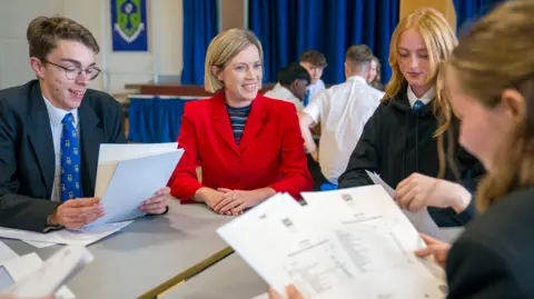 Jenny Gilruth sits with pupils opening their exam results 