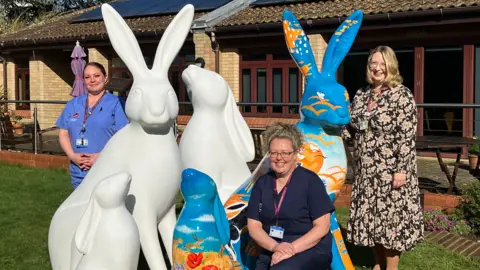 St Elizabeth Hospice Three women stood with three white hare sculptures and two blue hare sculptures