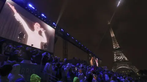 Shutterstock Celine Dion seen on a big screen next to the Eiffel Tower