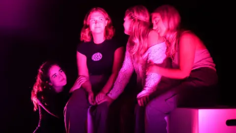 Rachel Foran Annie McIlwaine, Orla Graham, Ellen Andrews, and Leah Williamson sit on stage in pink lighting