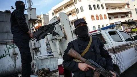 EPA Two Syrian security troops man a checkpoint in Latakia - both carrying machine guns with one stood on the back of a truck