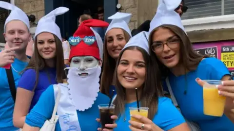 Carla Fowler/BBC A group of drinkers dressed in Smurf outfits holding drinks 