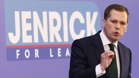 Getty Images Robert Jenrick makes a point as he gaves a speech against a "Jenrick for leader" backdrop