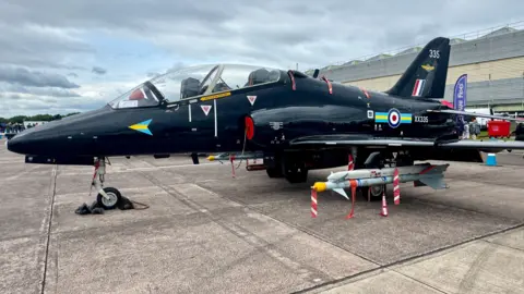 A black military plane with the number 335 on the tail of the plane