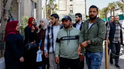 Reuters Victims' families gather outside the Palace of Justice, on the opening day of the trial of Atef Najib, former head of Political Security in Deraa under ousted president Bashar al-Assad, in Damascus, Syria (26 April 2026)