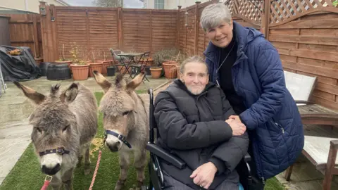 Mr and Mrs Crewdson pose next to the two miniature donkeys James and Bertram