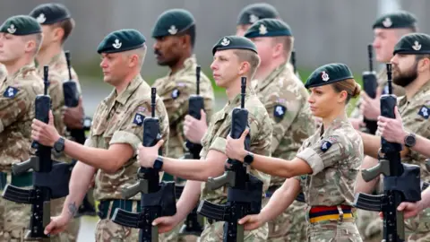 Getty Images Junior officers in the Royal Army Medical Corps holding rifles and dressed in camouflage.