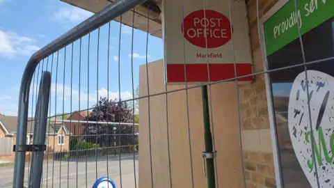 Post office sign and railings around boarded up shop