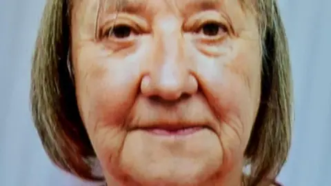 A woman with short blonde-ish hair and brown eyes looks into the camera