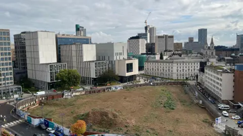 A large building site in the middle of Leeds surrounded by buildings 