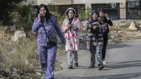 Getty Images Women leave an area where a residential building was hit in an Israeli strike, in Aramoun, Lebanon (13 November 2024)