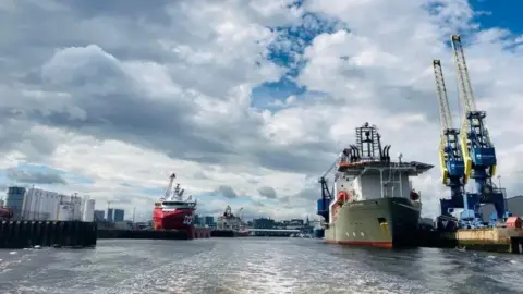 BBC An image of large vessels in the water of Aberdeen harbour, with the city skyline in the background.