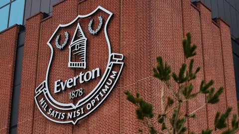 An Everton emblem seen on the exterior of the Hill Dickinson Stadium before the Premier League match between Everton and Tottenham Hotspur at Hill Dickinson Stadium