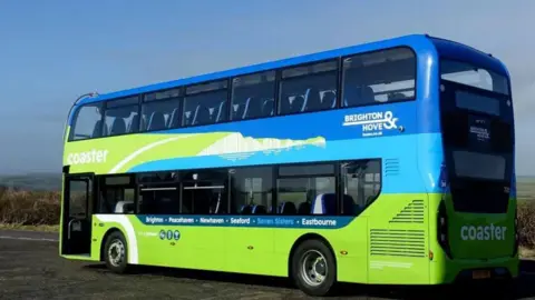 A blue and green double-decker bus parked on a roadside