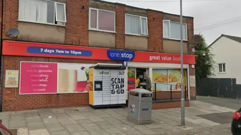 Google The outside of a convenience store in a brick building. 
