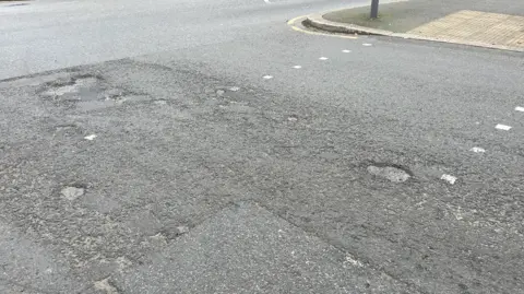 A downward view of a damaged road in Jersey.