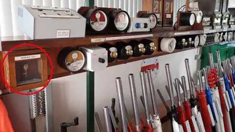 RAIB A row of railway signalling levers, with a key inside a wood and glass box circled on the left side of the picture