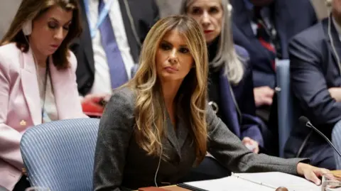 Melania Trump, sitting in a chair at the US with a binder open before her, presides over a United Nations Security Council meeting
