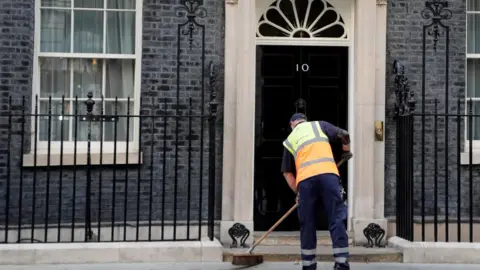 A man sweeping the road outside 10 Downing Street.