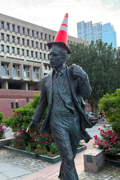 A statue of a man with a traffic cone on its head.