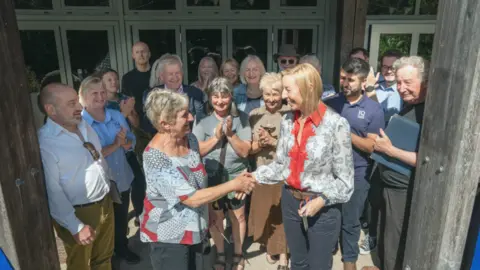 Derbyshire Eco Centre A celebratory hand-shake in front of a crowd at the centre's front door