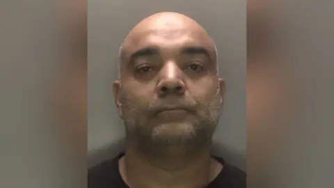 Leicestershire Police An image of Zakira Jawaid staring at the camera after he was arrested by police.