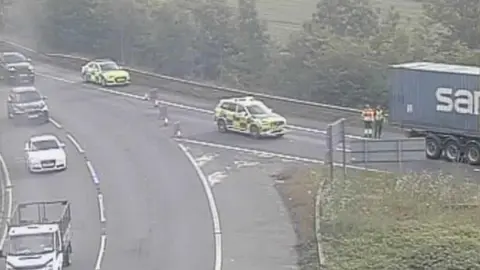 Two emergency vehicles parked by the side of a busy road.