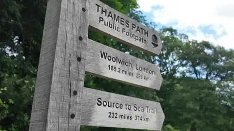 A wooden sign marking the start of the Thames path.