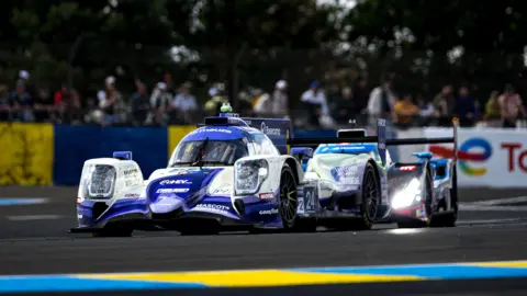 Nielsen Racing Two racing cars one in front of the other on a racing track.
