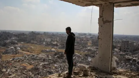 A Palestinian man standing in the ruins of a building