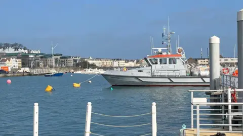 The leopardess in St Peter Port Harbour - A grey boat with an orange roof attached to a yellow buoy. 