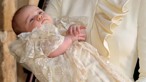 John Stillwell/WPA Pool/Getty Images A baby Prince George in a cream outfit during his christening in 2013
