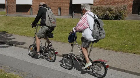 Two elderly people on bikes