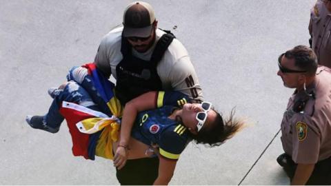 A Colombian fan being carried by a policeman after getting injured before the 2024 Copa America final