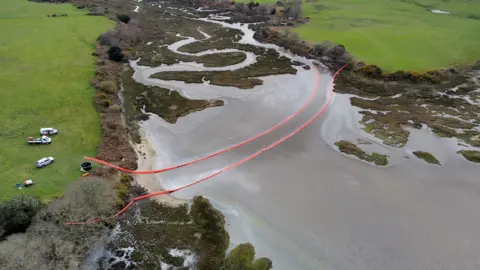 PA Oil is visible in the water of Poole Harbour, Dorset, following an oil leak from a pipeline at an onshore oil field