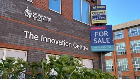A view of the Innovation Centre with a for sale sign attached to the corner.