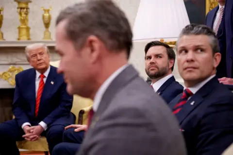 US President Donald Trump, National Security Adviser Michael Waltz, Vice-President JD Vance and Defence Secretary Pete Hegseth, all seated, at a news conference in the White House Oval Office.