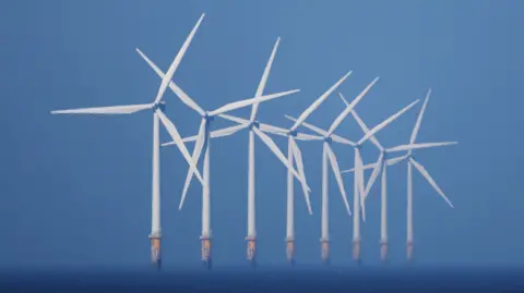 Eight offshore wind turbines in a line at sea.