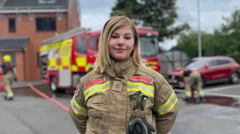 Firefighter stood in front of a fire engine and crew