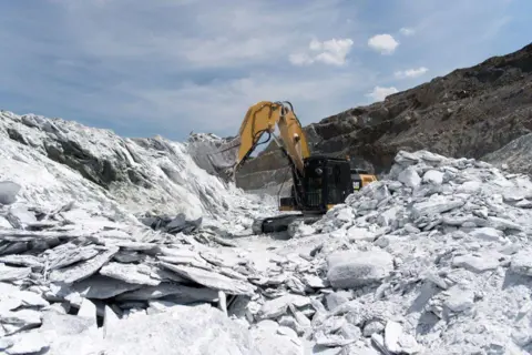 Getty Images An excavator extracting ore from the talc vein in a quarry