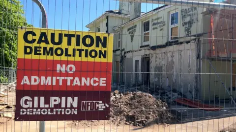 A demolition sign on metal fencing around the Seabury Hotel which is being demolished