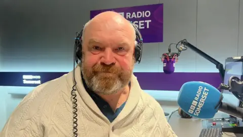 Council leader Bill Revans - A man in a radio studio wearing headphones sitting by a microphone