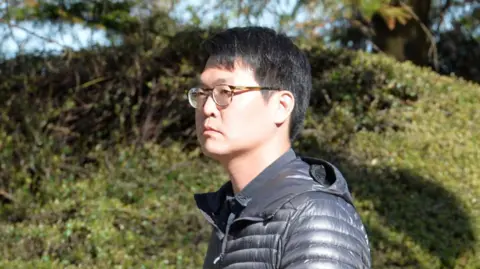 Ju Young Um arriving at court wearing a black puffer jacket