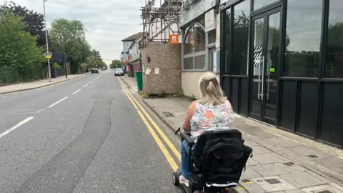 Tony Fisher/BBC Lynda Bell using her scooter on the road