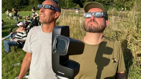 Michelle Adamson/BBC Peter Meynell în stânga în gri și Anthony în kaki, cu ochelari Eclipse și kit foto