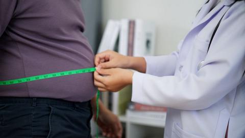Clinician measuring the waist of an overweight man
